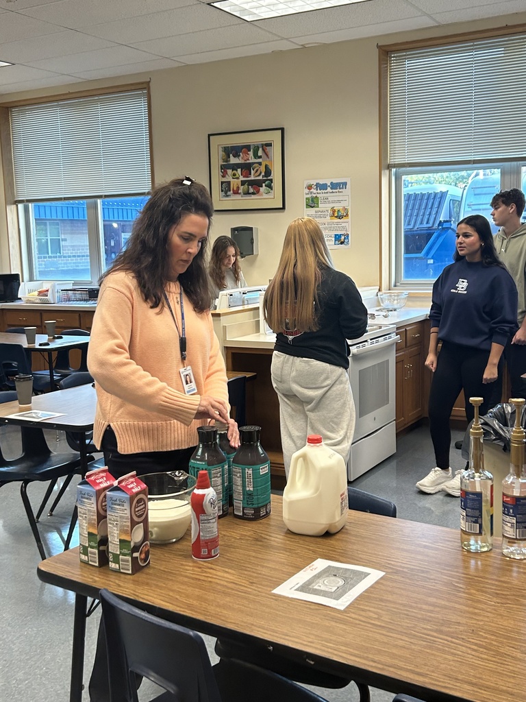 Mrs. Wallace is opening jugs of Coffee Cold Brew at a table with a gallon of milk, whipped cream and half and half.