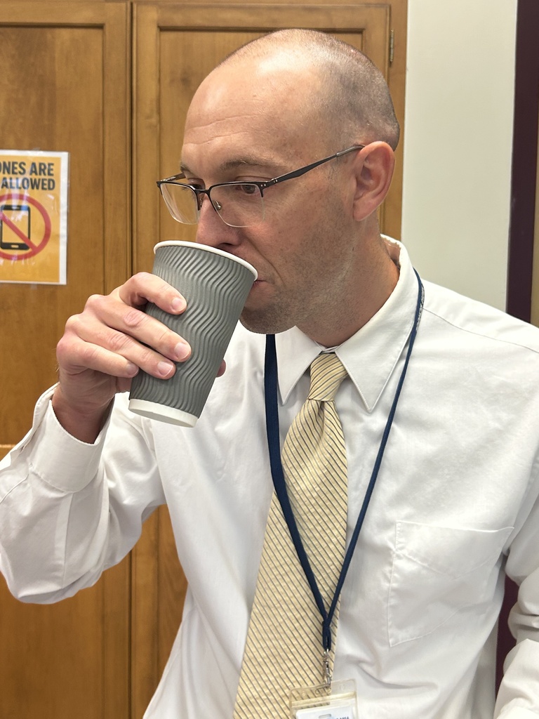 Mr. Stamy takes a sip of the student's coffee creation from a disposable coffee cup.