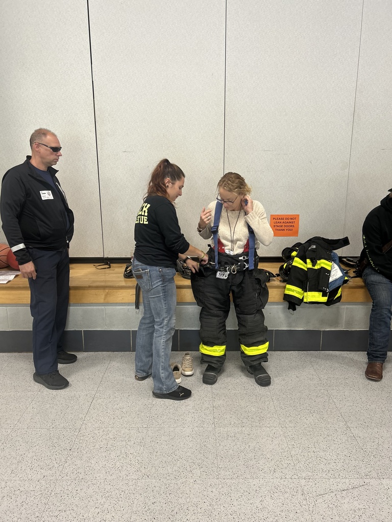 Third grade teacher is fitted with a firefighter uniform.