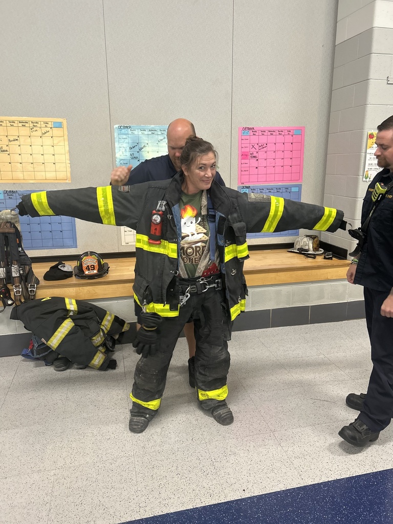 Paraprofessional being fitted into a firefighter uniform.