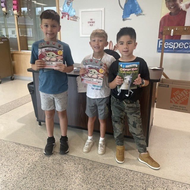 Three smiling students proudly display the books they selected from the Blazer Education Foundation Book Vending Machine.