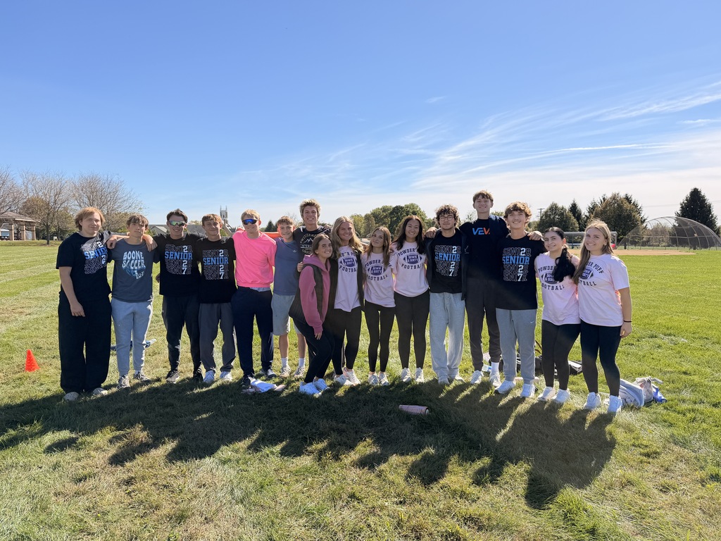 16 HS student helpers standing on a field.