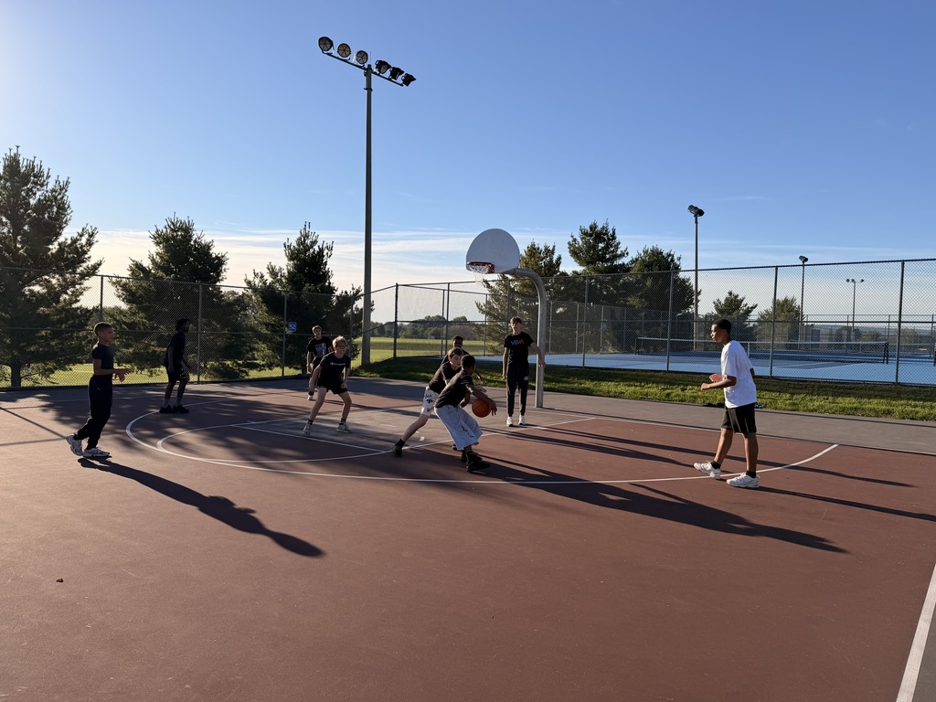 Students playing basketball outside on a basketball court