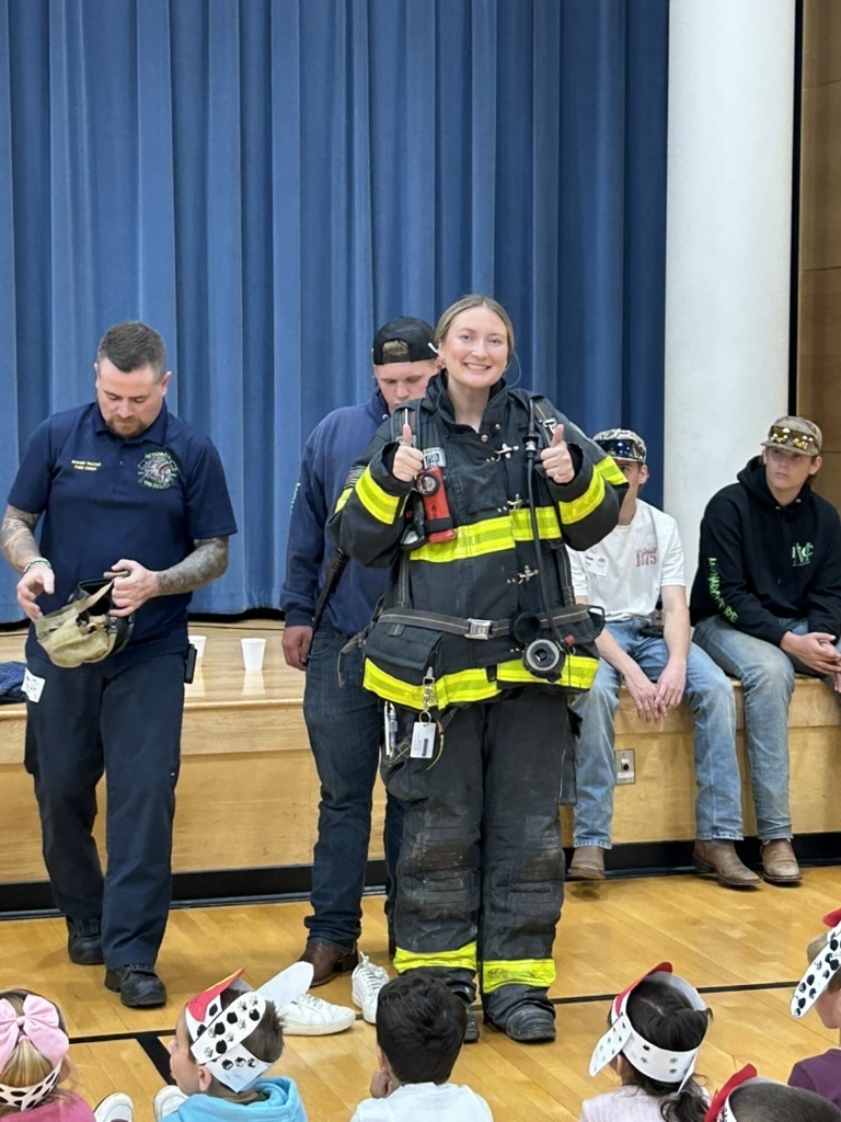 Teacher wearing a firefighter suit to show students that you should not be scared if a firefighter comes to help in case of emergency.