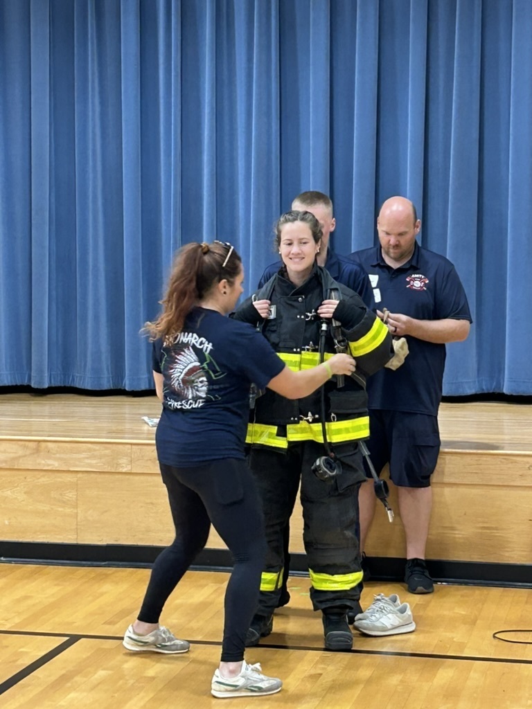 Teacher wearing a firefighter suit to show students that you should not be scared if a firefighter comes to help in case of emergency.