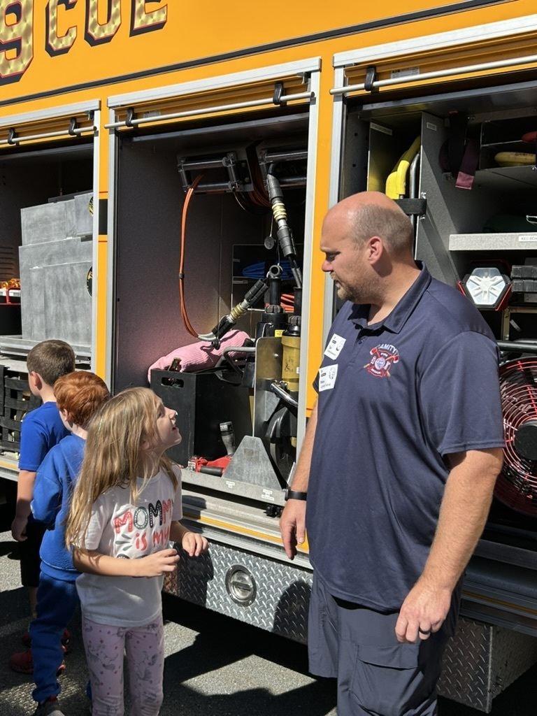 Firefighter answers a question from a student while standing next to a firetruck