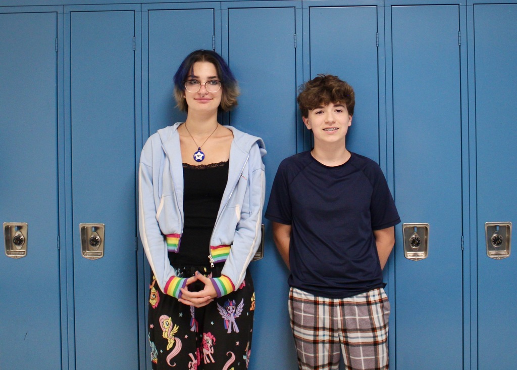 Students standing in front of lockers wearing pajamas.