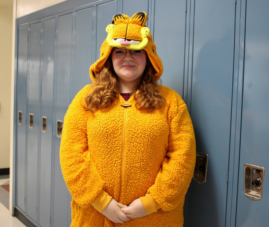 Student standing in front of lockers wearing pajamas.
