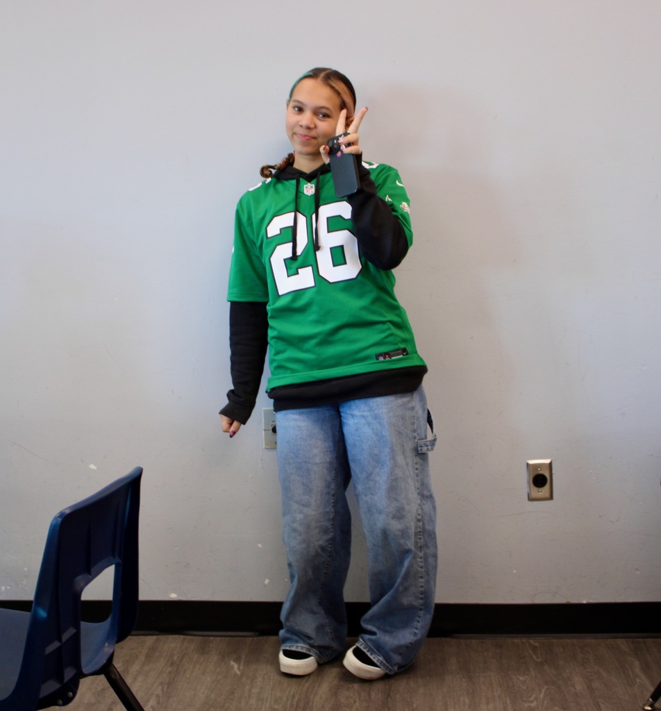 Student making a peace sign with their hand while wearing an Eagles jersey