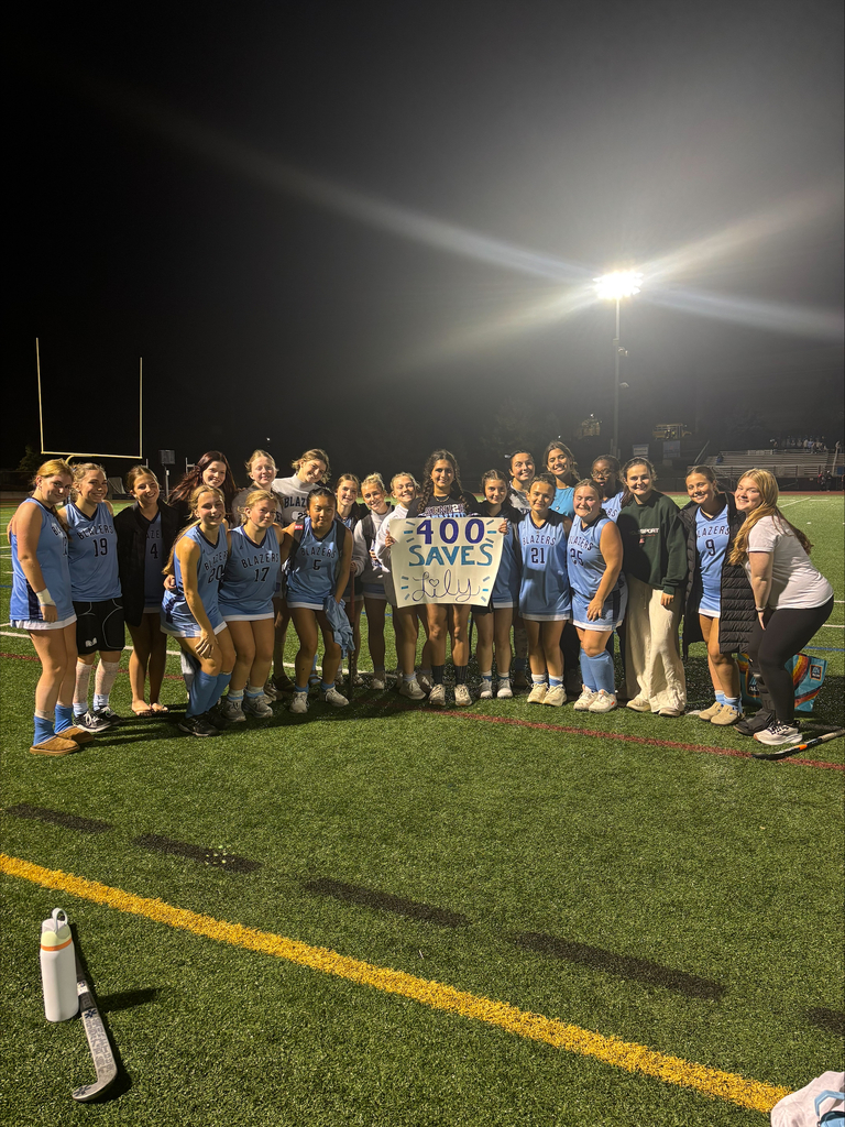 Field Hockey team gathered around student holding a sign that reads 400 Saves Lily