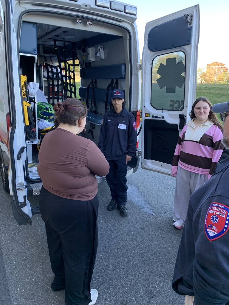 Two students learn about EMS work standing near the back of an ambulance