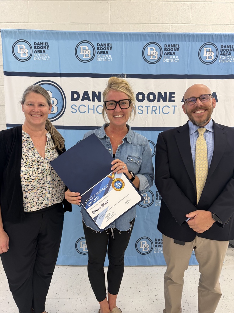 Melanie Hefter, Bonnie Blatt and Tom Voelker stand in front of a DBASD step and repeat banner. Bonnie is holding her Sweet Impact Award certificate. All are smiling.