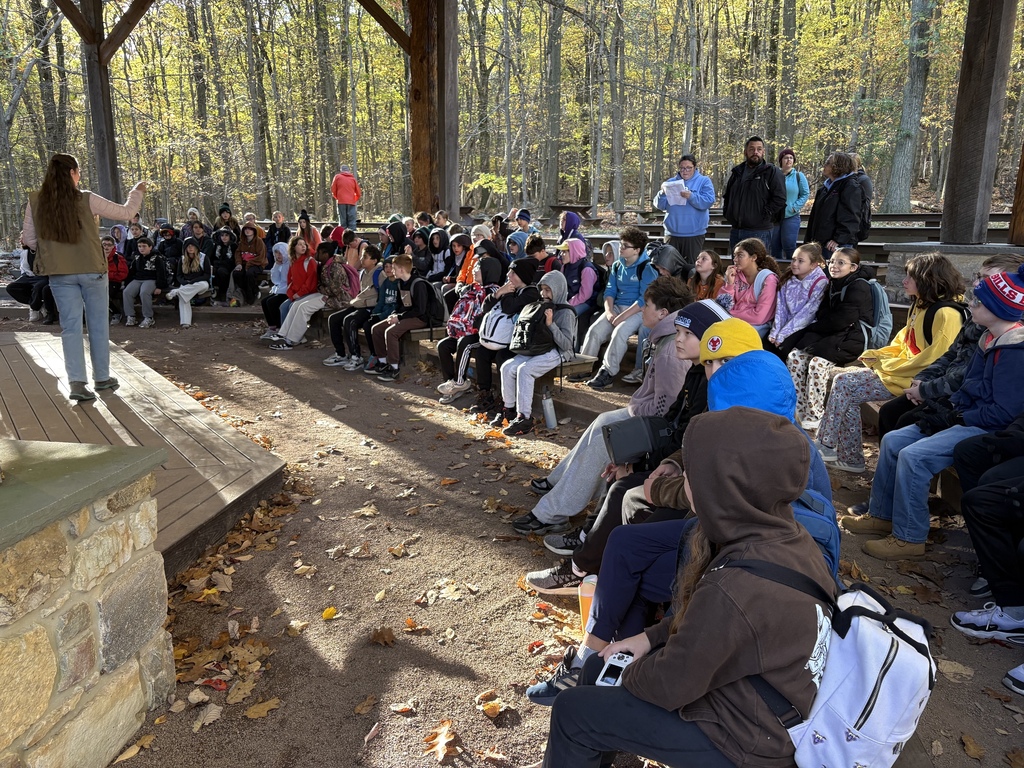 Sixth-grade students sit in an outdoor pavilion at Hawk Mountain while a presenter introduces their educational program.