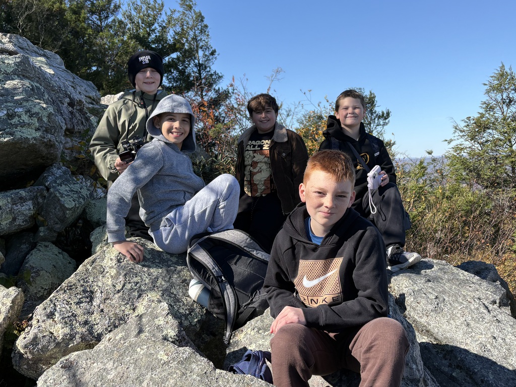 Five sixth-grade students pose for a photo while taking a break on the rocky summit at Hawk Mountain.