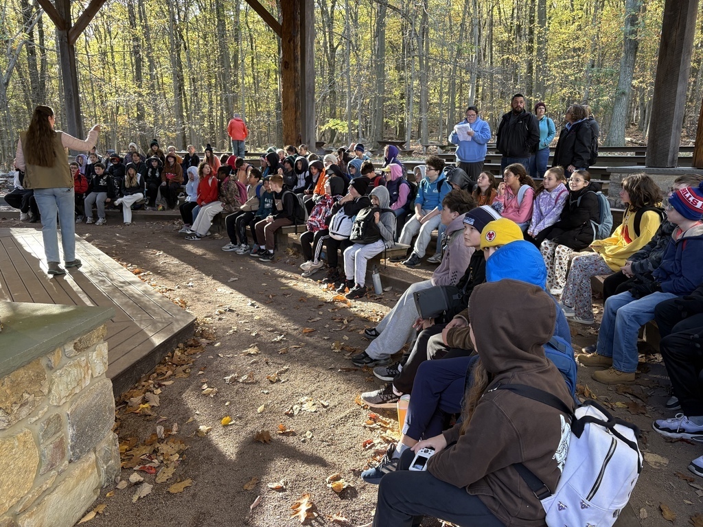 Sixth-grade students sit in an outdoor pavilion at Hawk Mountain while a presenter introduces their educational program.