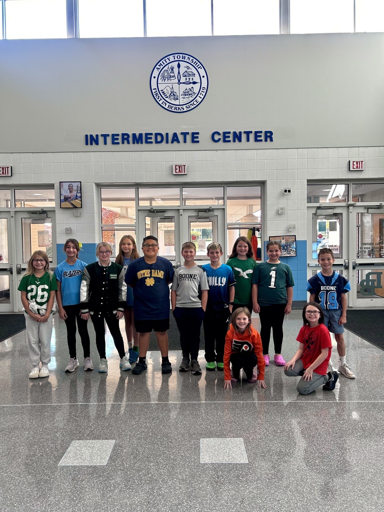 A group of 12 intermediate center students pose in their team attire in the lobby of the building.