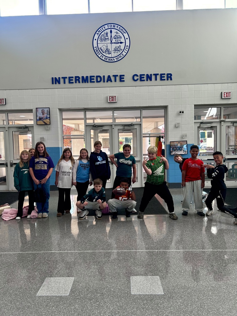 A group of 13 students pose in their team attire in the lobby of the Intermediate Center.
