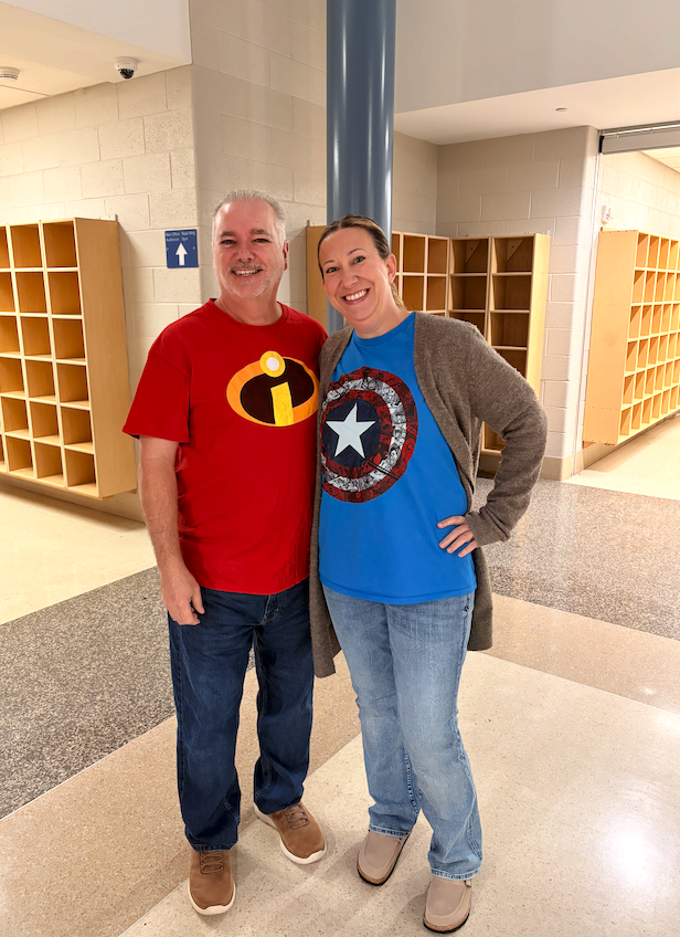 Two staff members pose showing off their Incredibles and Captain America t-shirts.