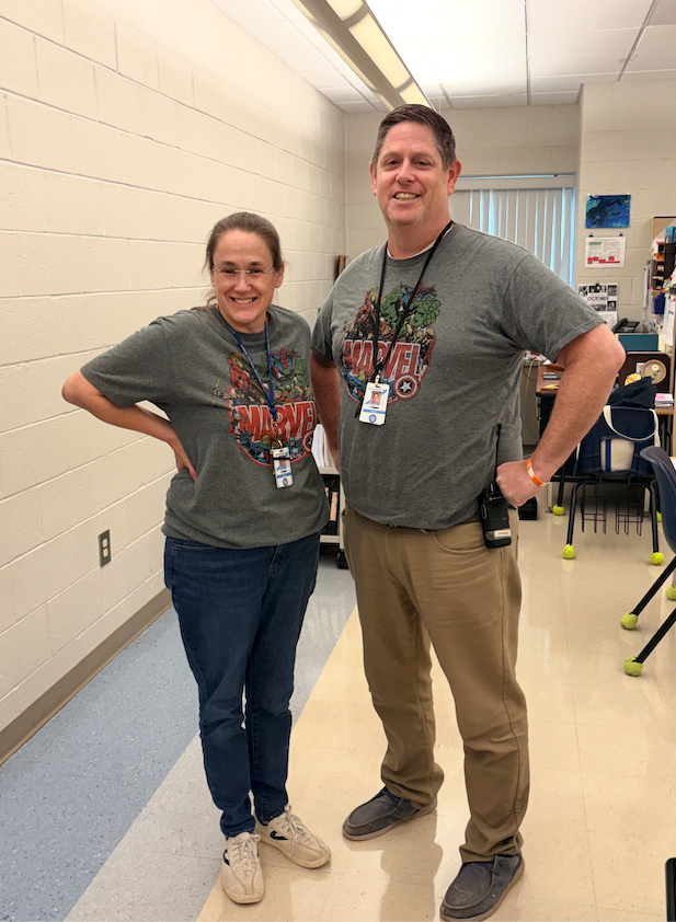 Two middle school staff members pose wearing the same Marvel Superheroes shirt