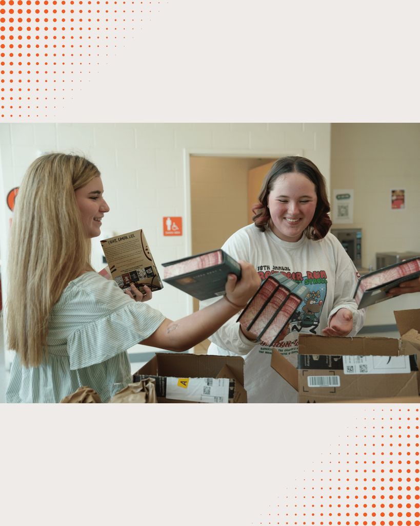 DCHS students opening boxes of newly donated books, unpacking and organizing them together