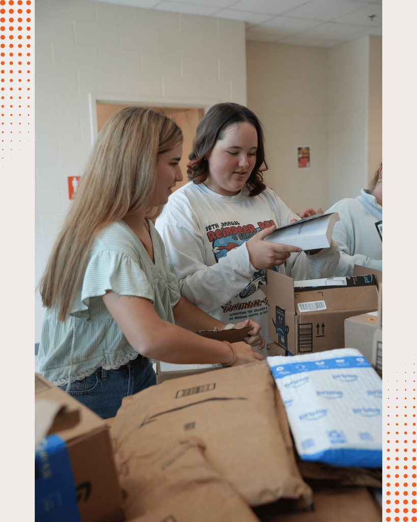 DCHS students opening boxes of newly donated books, unpacking and organizing them together