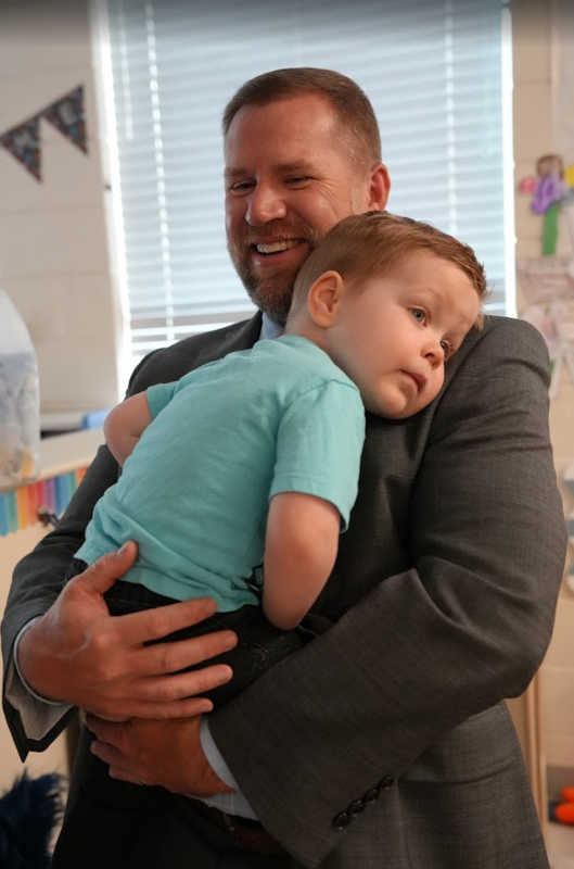 superintendent holding preschooler