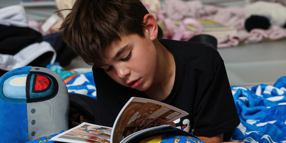 A student reading a book on a blanket