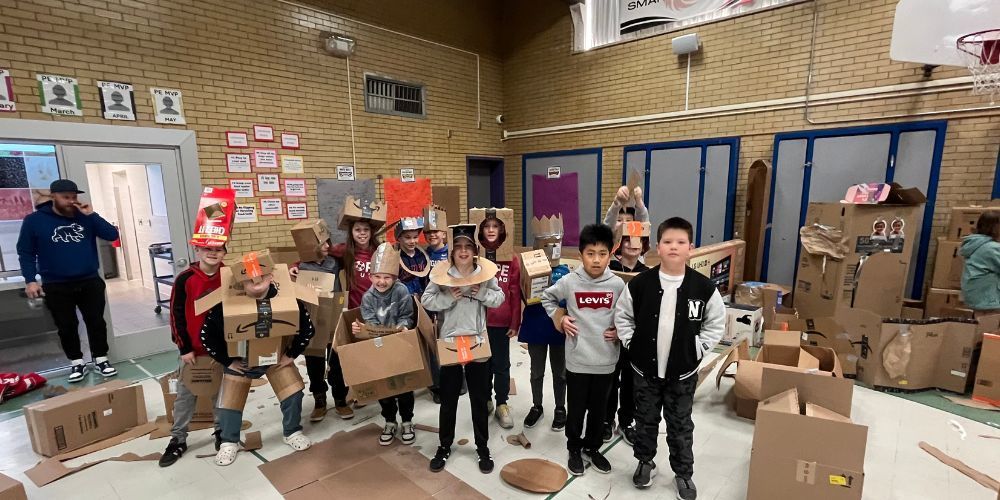 4th graders with boxes that they made into robots and forts in the gym
