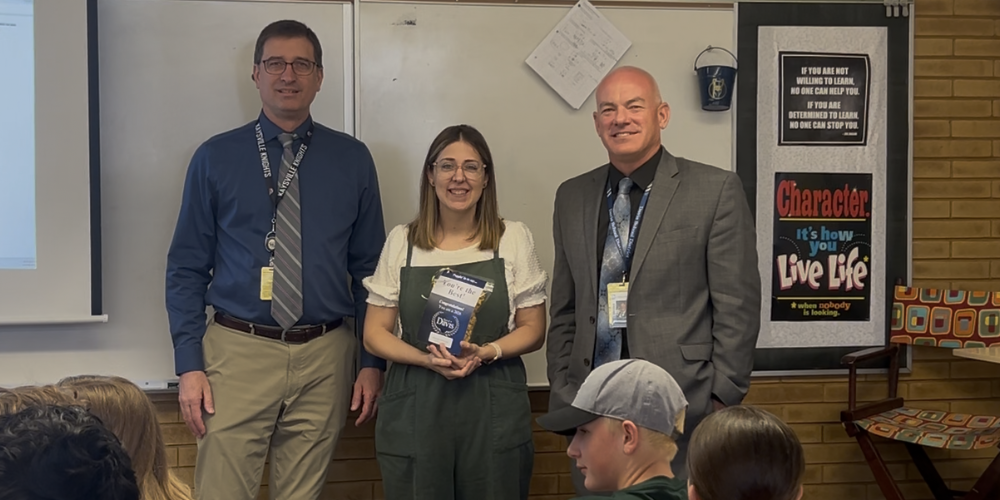 image of 3 people standing in front of a white board. middle person is holding a best in davis award