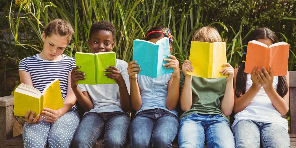 Picture of kids reading book outside.