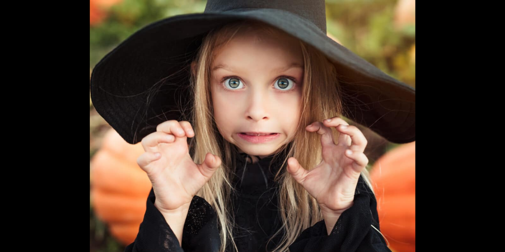 photo of child with pointed black hat and pulling a scary face.