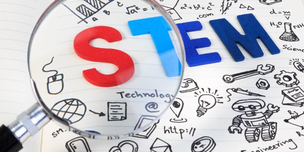 photo of little drawings and  the word STEM in a magnifying glass