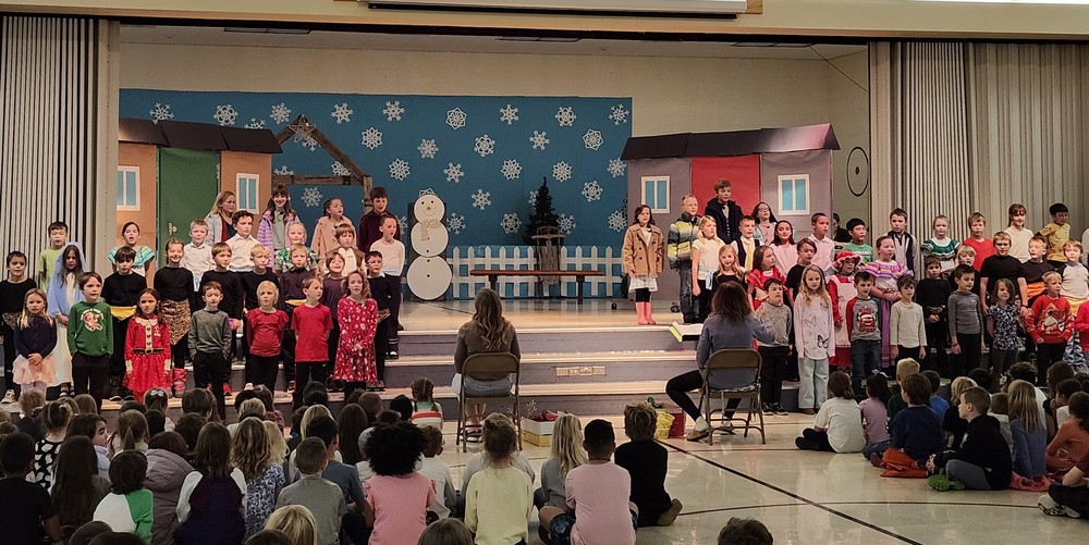 Children on the gym steps in front of the December in our Town stage.