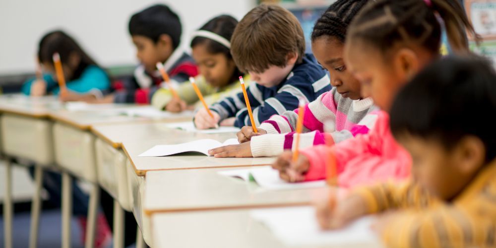Kids testing at desks with pencils.