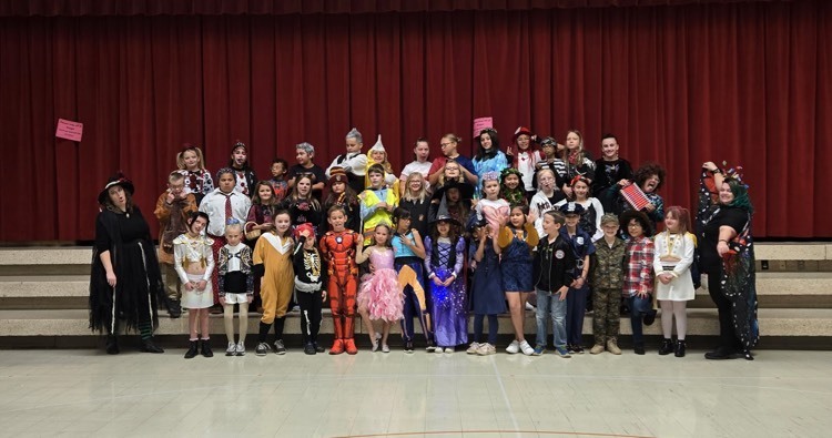Meadowbrook choir students wearing Halloween costumes standing on steps after their performance for the school.