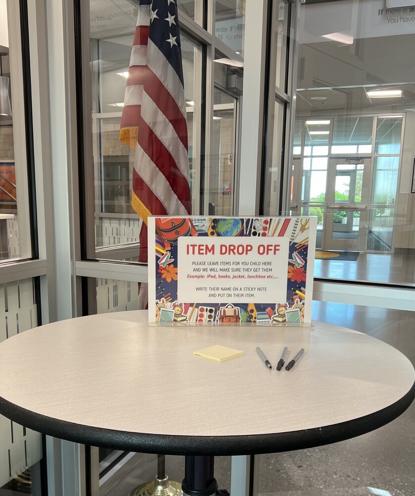 Item Drop Off image. A table with the sign of Item Drop Off and an American flag in the background