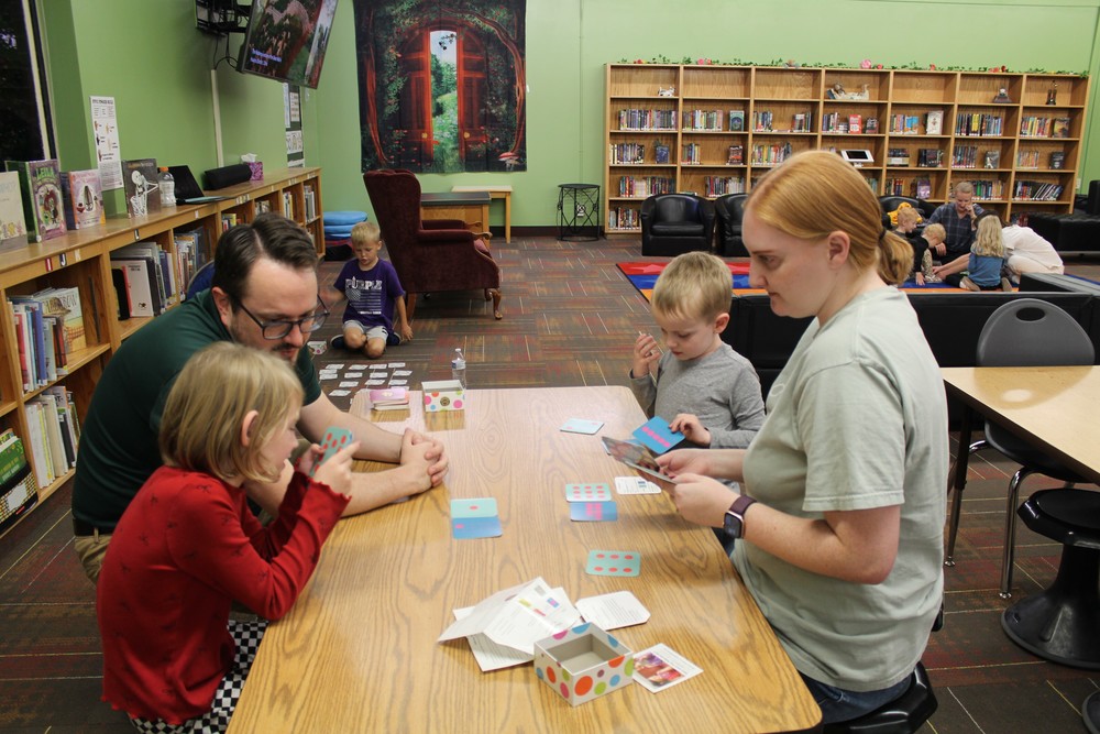Family of four playing a math game in the school library.