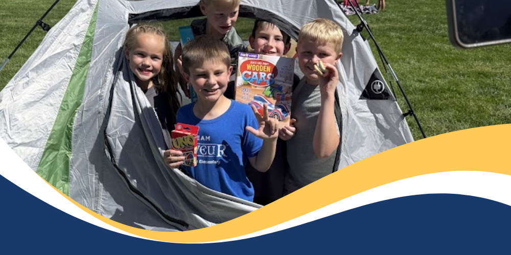 Students in a tent holding books, card games, and squishes.