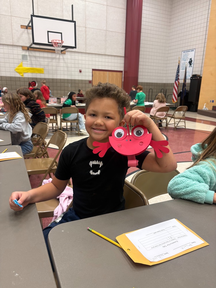 Boy holding a handmade lobster created out of construction paper with googly eyes.