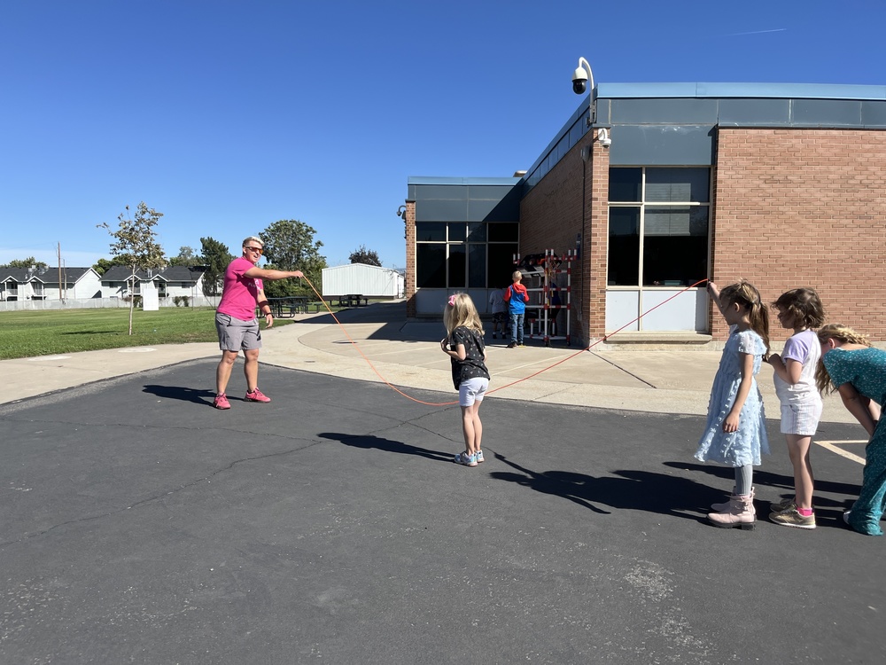 Coach Jolly playing jump rope with students out at recess