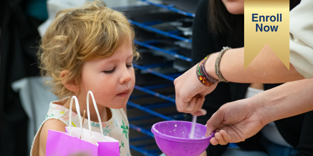 Preschool student peaking inside a bucket during an activity with the ribbon on image that says Enroll now