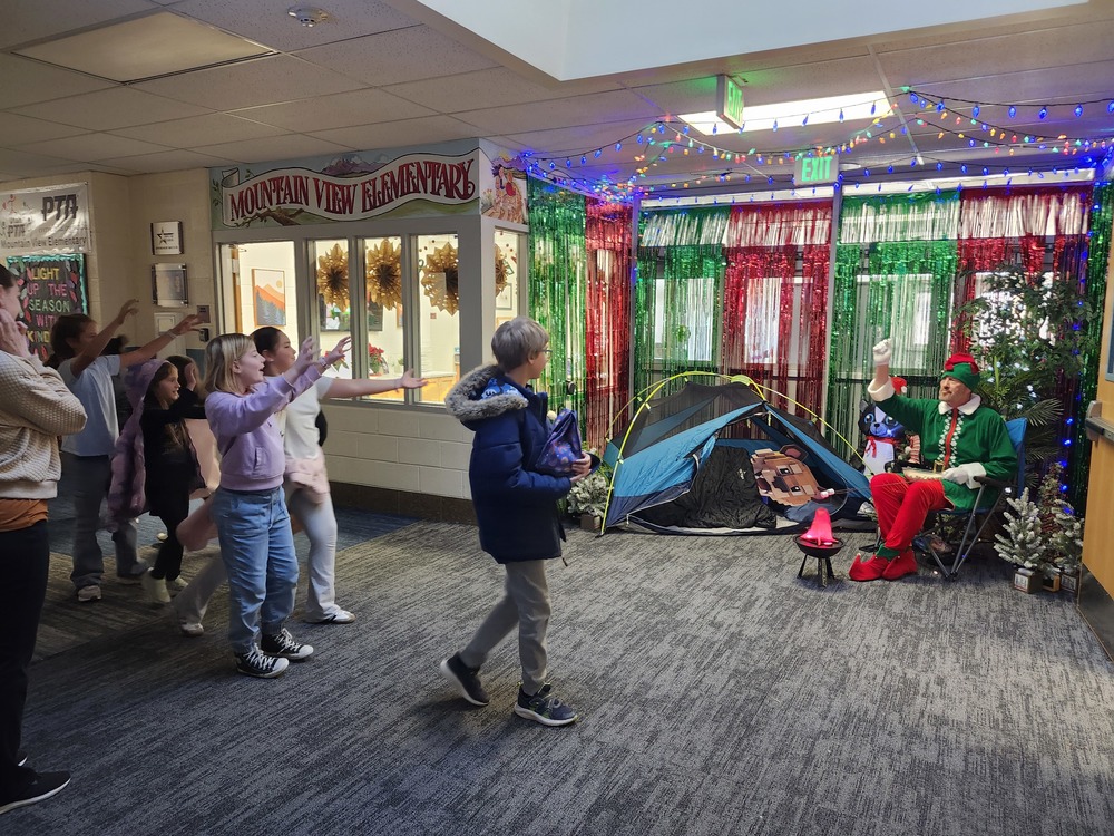 Mr. Nash as Pinky the Elf in front of a decorated hallway throwing marshmellows at kids.