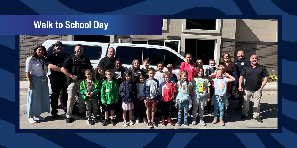 Students, administrators, and police posing in front of a police vehicle for Walk to School Day