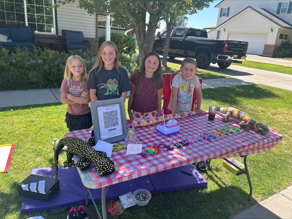Children behind a table with lizard toys.