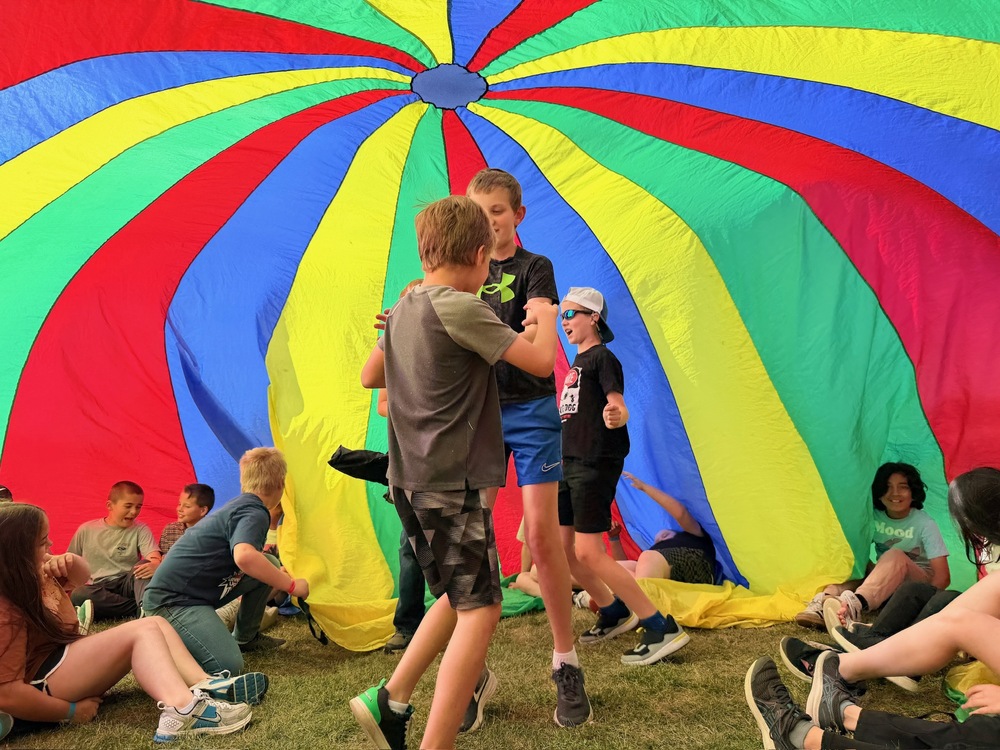 Students playing underneath colorful parachute