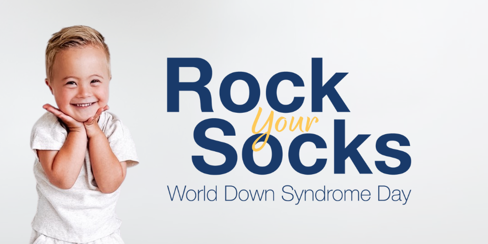 An image of a young student holding their hands next to their face. He is wearing neutral colors. The rest of the graphic says: "Rock Your Socks World Down Syndrome Day."