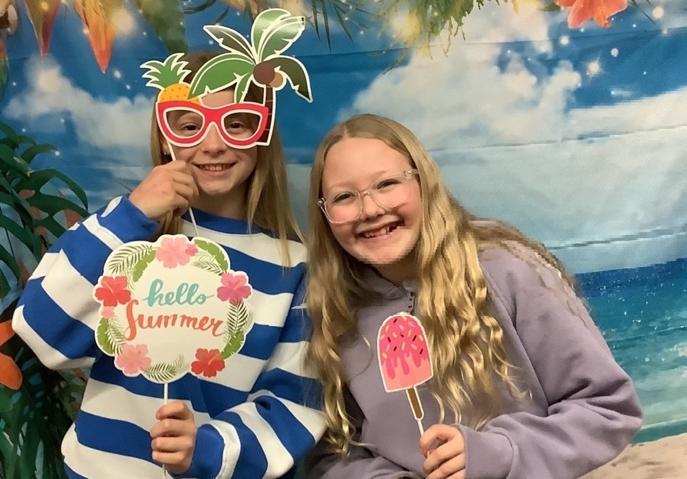 Two girls at photo booth with beach themed props