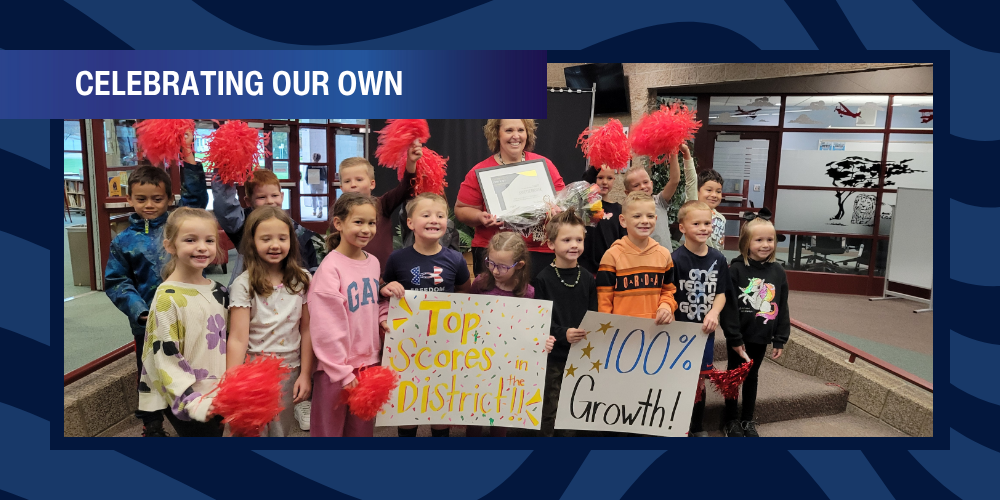 Mrs. Brewer and students holding signs and pom poms.