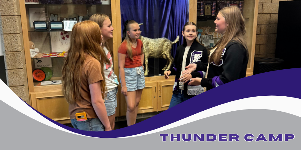 School Officers talking to female students in front of display cases with purple, white, and gray wave with the words Thunder Camp