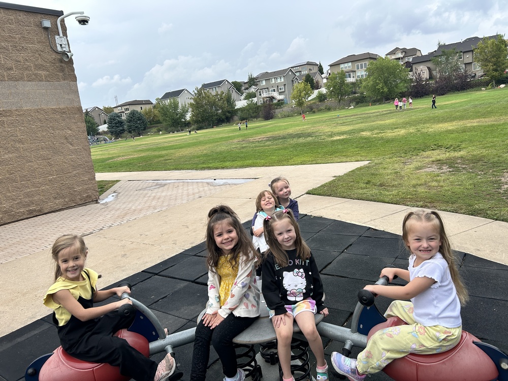 Kindergarteners playing on a wobble toy on the playground
